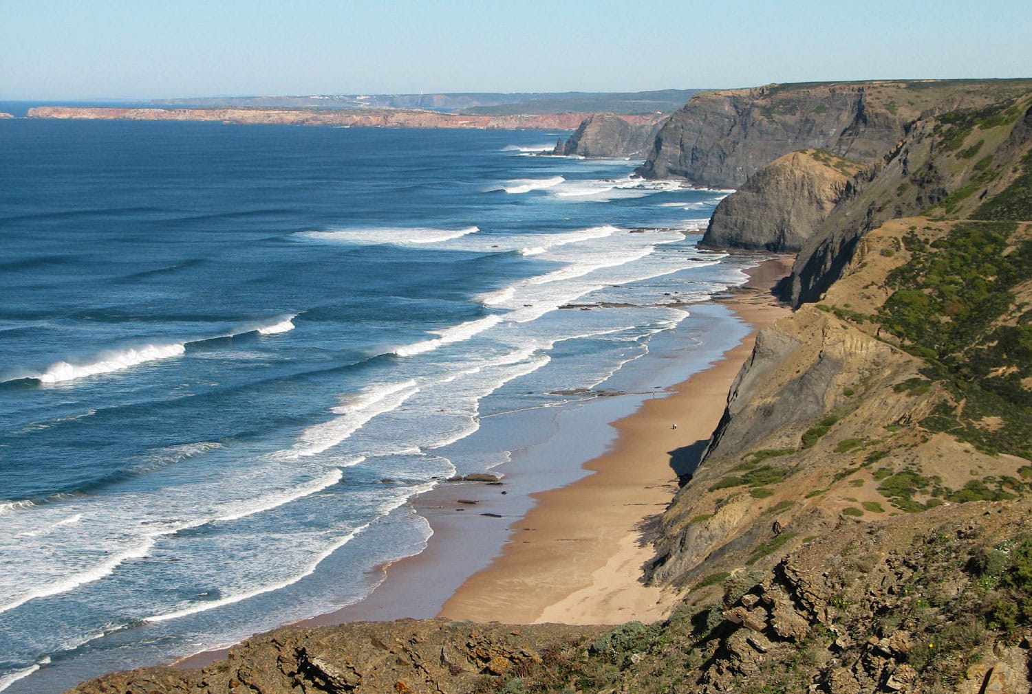 Dramatic cliffs at Praia da Cordoama beach with waves rolling in